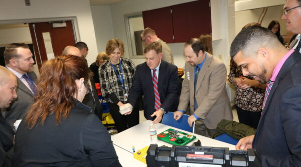 A group of educators looks over a STEM exercise involving an egg carton and other household objects.