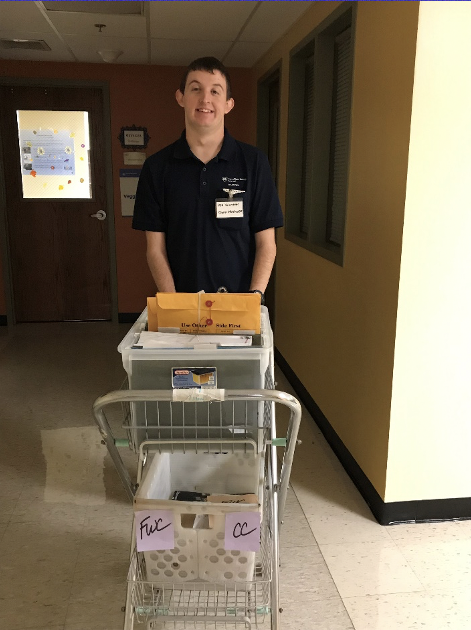 A Project SEARCH intern pushes a mail cart in a hallway