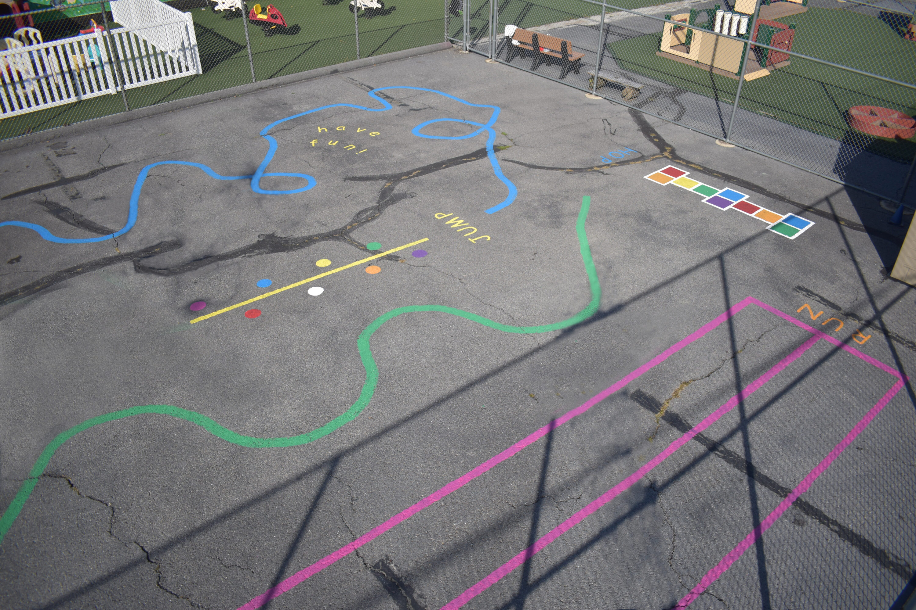 Aerial photo of a playground painted with lines of pink, green, and blue to encourage children to run and play.